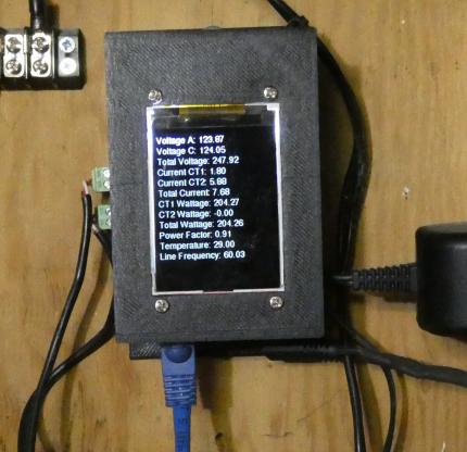Image of ATM90E32AS CircuitSetup based power meter showing screen, in case mounted near electrical panel
